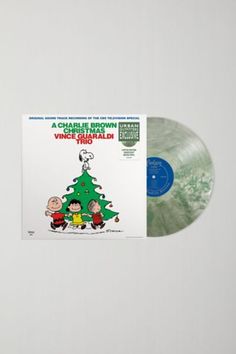 a charlie brown christmas vinyl album on a white wall with a green tree and peanuts around it