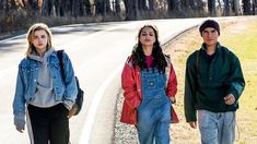 three people are walking down the road together