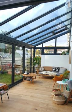 a living room filled with furniture and lots of glass on top of wooden flooring