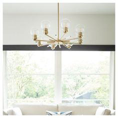 a living room filled with furniture and a large window next to a white couch under a chandelier