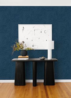 two black tables in front of a blue wall with a white painting on the wall