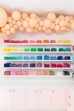 a room with shelves filled with lots of different colored items and balloons hanging from the ceiling