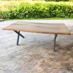 a wooden table sitting on top of a cement floor next to a green planter