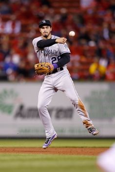 a baseball player throwing a ball on top of a field in front of an audience