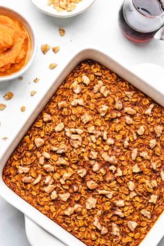 a casserole dish filled with granola and nuts next to bowls of mashed potatoes