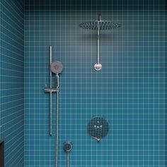 a blue tiled bathroom with shower head and handset