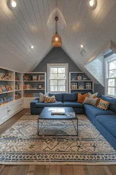 an attic living room with blue couches and white bookcases on the walls