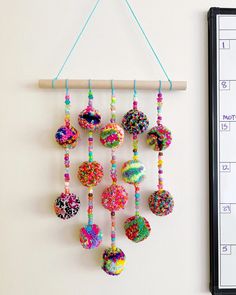 a calendar hangs on the wall next to a handmade mobile with colorful beads hanging from it