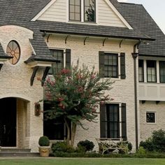 a large white brick house with a clock on it's face and two story windows