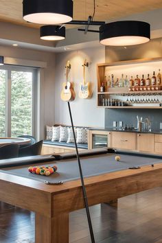 a pool table in a room with several guitars on the wall