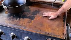 a person that is standing over an old stove with a pan on top of it