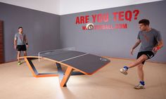 two men are playing ping pong in an indoor room with a ping pong table