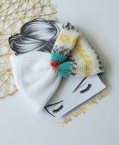 two knitted hair clips on top of a book next to a golden wire net