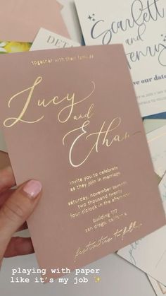 a person holding up a pink wedding card