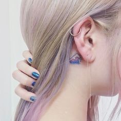 a woman with blue and pink hair has ear piercings on her ears