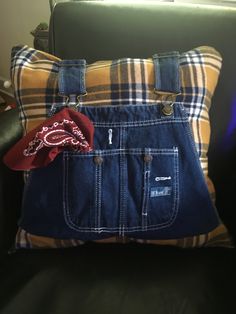 a blue jean purse sitting on top of a black couch next to a brown pillow