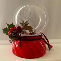 a snow globe sitting on top of a white counter next to a christmas tree ornament