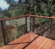 a wooden deck with metal railing and trees in the background