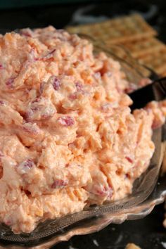 a glass bowl filled with potato salad next to crackers