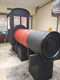 an orange and black telescope sitting on top of a metal stand in a room with other items