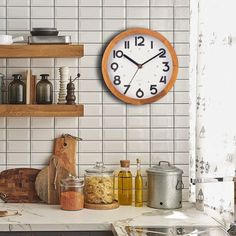 a kitchen with a clock on the wall and various cooking utensils in front of it