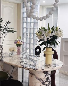 a marble dining table with vases and flowers on it