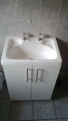 a white sink sitting next to a tiled wall