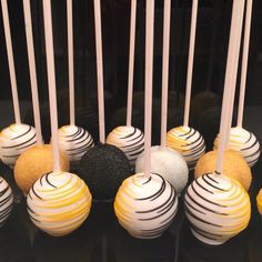 there are many cake pops with white and black frosting on the sticks in front of them