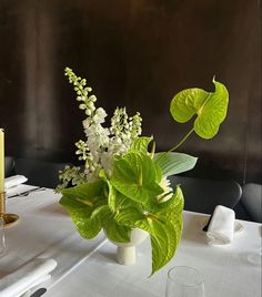 a vase with flowers and greenery on a table in a restaurant or dining room