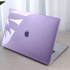 an apple laptop computer sitting on top of a wooden table next to a potted plant