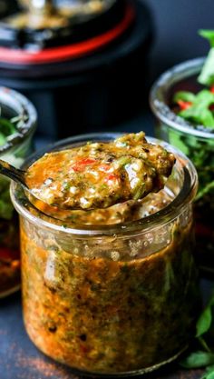 a jar filled with food sitting on top of a table next to some salads