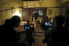 a group of people standing around in a room with cameras on the floor and behind them are televisions