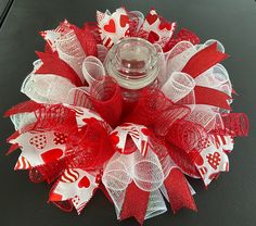 a red and white valentine's day wreath with a candle in it on a table