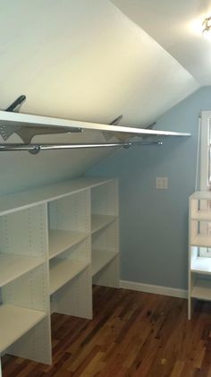 an empty room with white shelves and wooden floors