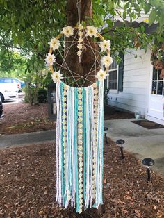 a wind chime hanging from a tree in front of a house with flowers on it