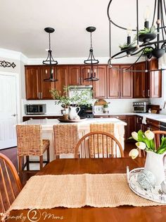 a dining room table and chairs with flowers in vases on the centerpiece next to an open kitchen door