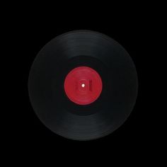 an old black record with red disk in the middle on a black background, taken from above