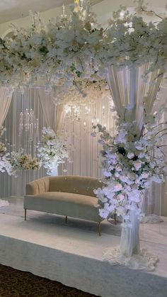 an elegant wedding setup with white flowers and chandelier on the wall behind it