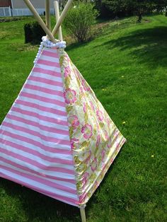 a pink and white striped teepee sitting in the grass