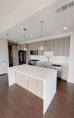 an empty kitchen with white counter tops and wooden floors