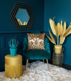 a living room with blue walls, gold accents and a leopard print pillow on the chair