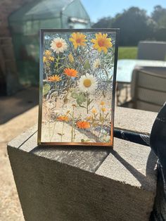 a card with sunflowers and daisies on it sitting on a stone ledge