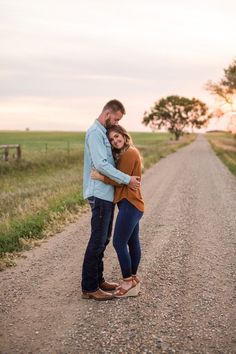 a man and woman hugging on the side of a dirt road