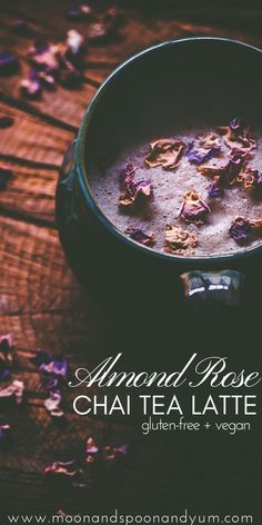 a bowl filled with chaatea latte next to flowers on a wooden table