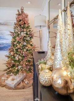 a christmas tree is decorated with gold and silver ornaments, while other holiday decorations are arranged around it