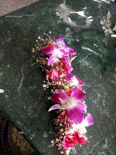 purple and white orchids are arranged on a green marble table