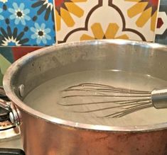 a large metal pot with whisk in it