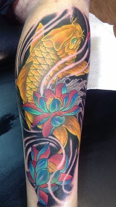 a colorful tattoo on the arm of a person with an orange and blue fish in it