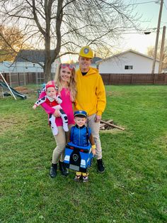 a man, woman and two children are posing for a photo in the grass with a fireman's costume on