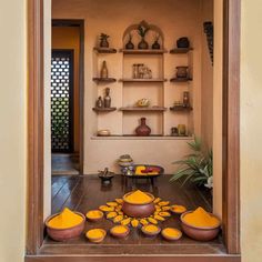 an open doorway with bowls and plates on the floor in front of shelves filled with vases